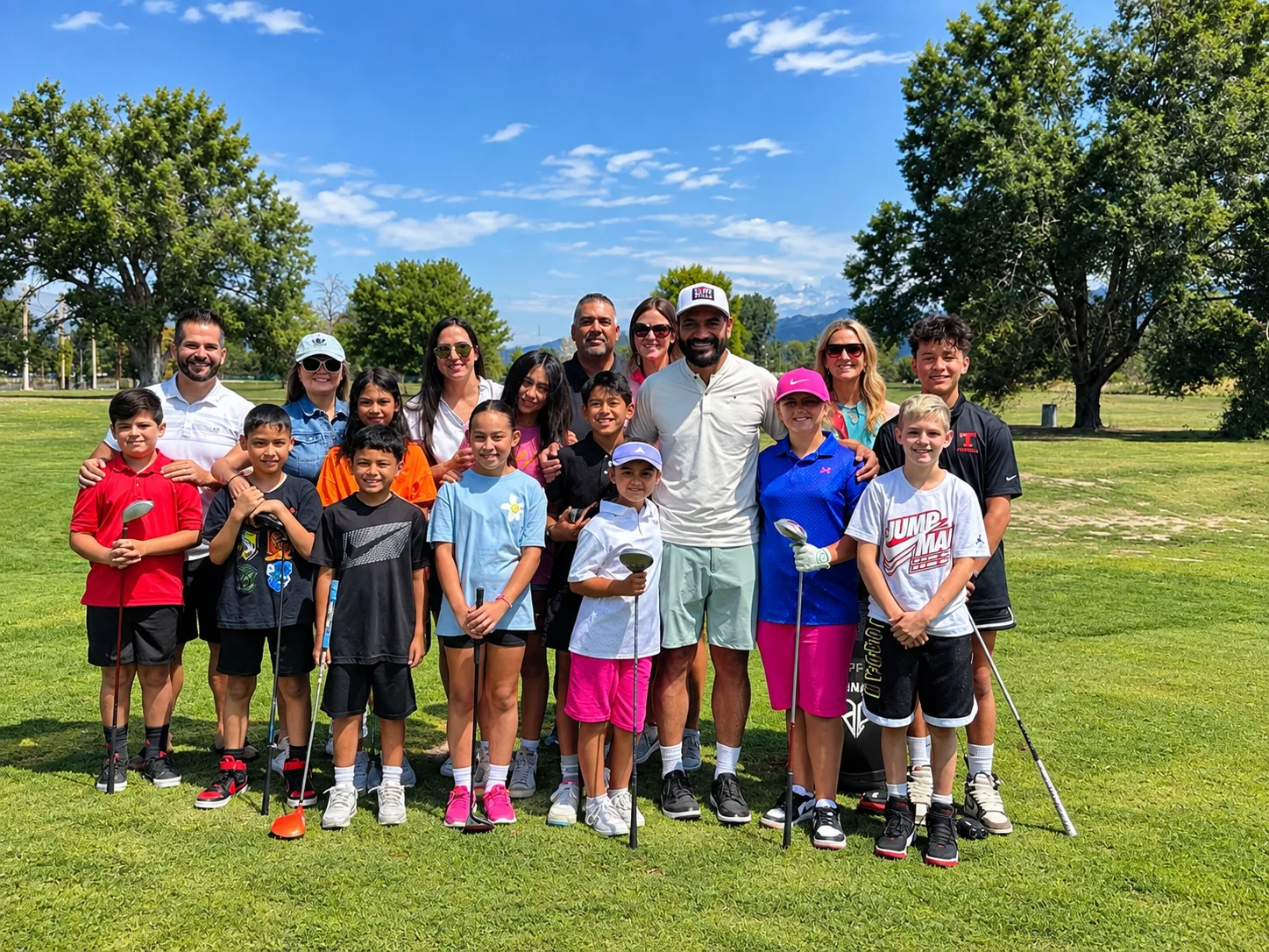 Junior golfers and adults smiling together on a sunny golf course
